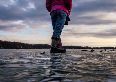 Girl standing on frozen lake at sunset