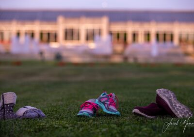 3 pairs of shoes in a field with a blurry building in the background